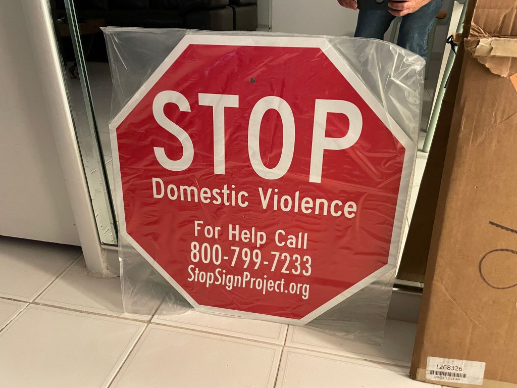 A manufactured aluminum Stop Domestic Violence sign showing the National Domestic Violence Hotline and StopSignProject.org